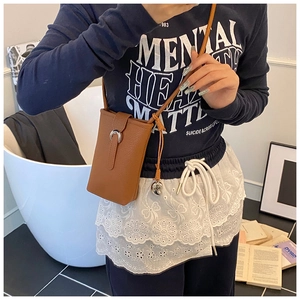Brown litchi grain bucket bag for women worn by a model in a cozy interior setting
