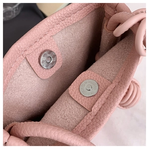 Detail of silver magnetic closure and interior suede texture on pink leather crossbody bag