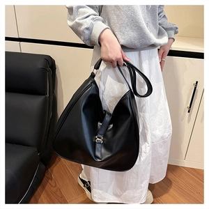 Detail of minimalist black tote bag with matte leather texture and golden metal ring