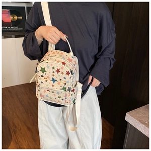 Detailed view of mini cream backpack with colorful star patterns and adjustable strap