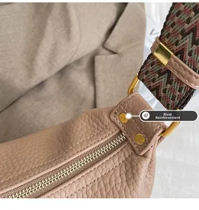 Detail of rivet reinforcement and golden zipper on beige leather crossbody bag