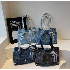 Detailed view of denim tote bags featuring metallic butterfly studs and lace pearl charms