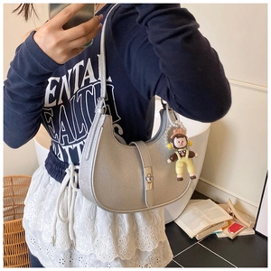 Detail of silver pebble leather hobo bag with zip closure and cute plush charm pendant