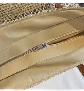 Detailed close-up showing the smooth metal zipper closure and woven texture of the straw bag