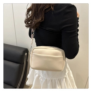Close-up of cream crossbody bag with lychee texture and adjustable wide shoulder strap