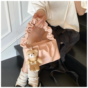 Detail of pink pleated PU shoulder bag featuring a cute plush bear fashion charm
