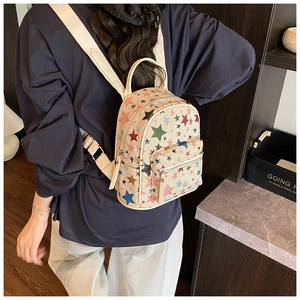 Detail of a cream mini backpack with colorful star patterns worn on the back