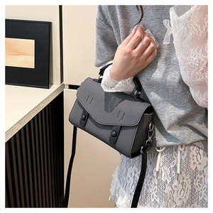 Detail of grey crossbody bag showing textured finish and black leather handle straps