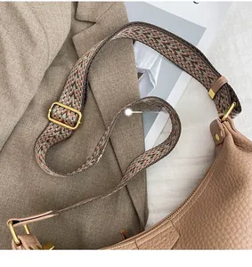 Detail of lychee pattern leather dumpling bag with colorful ethnic style wide shoulder strap