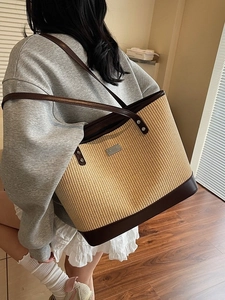Large capacity woven straw tote bag with brown leather trim and metal rivet accents