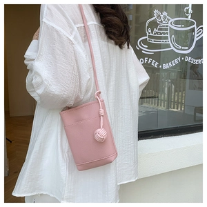 Pink bucket crossbody bag with litchi grain texture and side woven knot detail