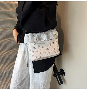 Detail of floral shoulder bag with lace edges and woven strap worn by a model