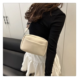 Detail of off-white lychee texture PU crossbody bag with striped wide shoulder strap