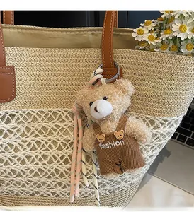 Detail of a cute plush bear charm with fashion embroidery hanging on a straw tote bag