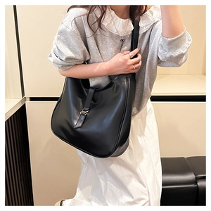 Close-up of the soft black leather texture and metal buckle detail on the large tote bag