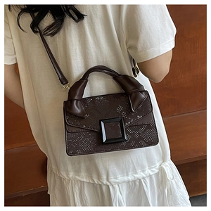 Detail of snake skin texture flap bag with black square buckle and knotted top handle
