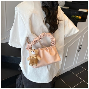Detail of light pink ruched handbag with soft cloud texture and plush teddy bear charm