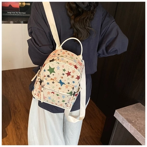 Detail of colorful star print on cream backpack with adjustable straps and front pocket