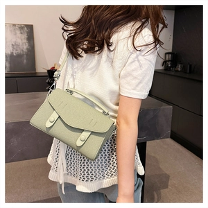 Detail of light green crossbody bag featuring flap closure and decorative buckles