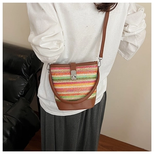 Detailed shot of a colorful striped woven straw bucket bag with brown leather strap