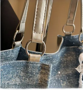Detail of blue glitter denim tote bag with silver leather handle and round metal ring
