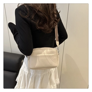Detail of lychee textured PU leather crossbody bag with wide woven shoulder strap