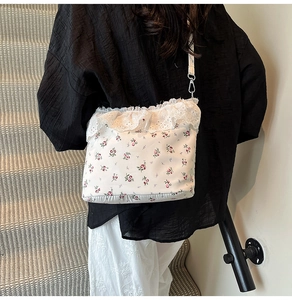 Close-up of floral crossbody bag with white lace frill trim and delicate pink patterns
