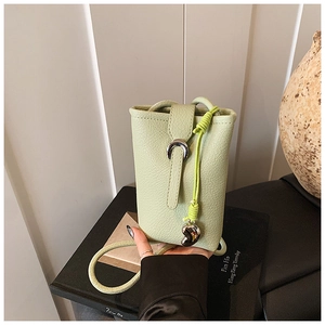 Détail du sac de téléphone en cuir vert clair avec boucle fer à cheval et breloque coeur