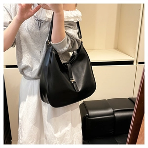 Detail view of large black matte leather tote bag featuring a buckle and hobo style structure