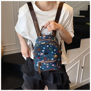 Mini denim backpack with colorful star embroidery worn by model in a minimalist room