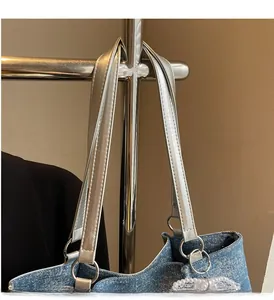 Detail of blue denim tote bag featuring silver metallic strap and pearl lace ornament