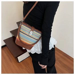 Detail of colorful rainbow woven crossbody bucket bag with brown leather strap and silver lock