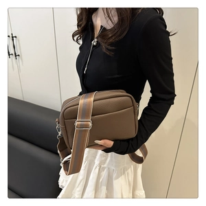 Detailed view of brown litchi pattern PU leather crossbody bag with wide striped strap
