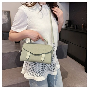 Detail of light green woven crossbody bag showing leather strap and modern clasp detail