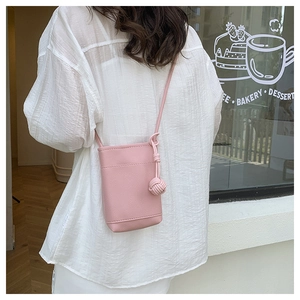 Pink pebbled leather mini crossbody phone bag with knot tassel detail on white shirt