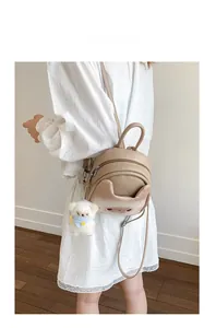 Close-up of cute cat-ear mini backpack in beige PU leather with a plush bear charm