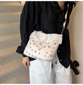 Close-up of floral crossbody bag featuring delicate white lace trim and pink flower patterns