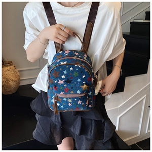 Detail of navy canvas backpack featuring colorful star embroidery and brown leather trim