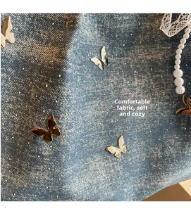 Detailed macro view of denim fabric with metallic butterfly ornaments and sequins