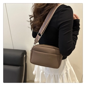 Detail view of lychee pattern leather crossbody bag with a wide woven shoulder strap
