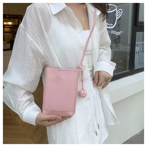 Pink lychee grain leather phone bag featuring a handmade woven ball charm detail