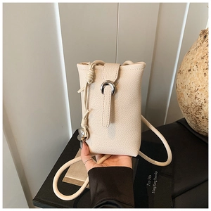 Vue détaillée du sac pour téléphone en cuir grainé crème avec boucle en U et pendentif cœur