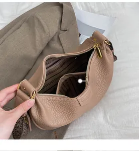 Detail of warm khaki dumpling bag with lychee grain leather and geometric woven strap