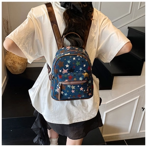 Detail of blue denim mini backpack with colorful star prints and brown leather straps