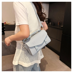 Detail of light blue-grey crossbody bag with fine texture and adjustable silver strap