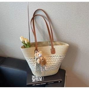 Close-up of woven straw tote bag with mesh detail, leather handles and cute bear charm