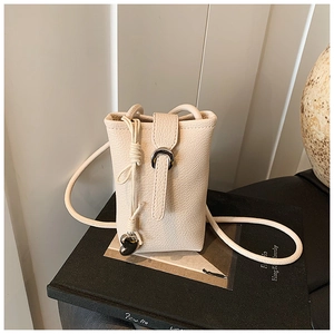 Close-up of beige lychee-patterned bucket bag with heart pendant and metallic detail
