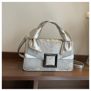 Detail of silver snake-pattern handbag with knot handle and black square buckle
