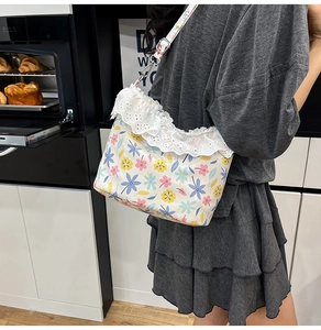 Detailed view of floral canvas crossbody bag with delicate embroidered lace trim detail