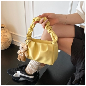 Detailed view of yellow ruched handbag with cute bear charm and fashion pendant